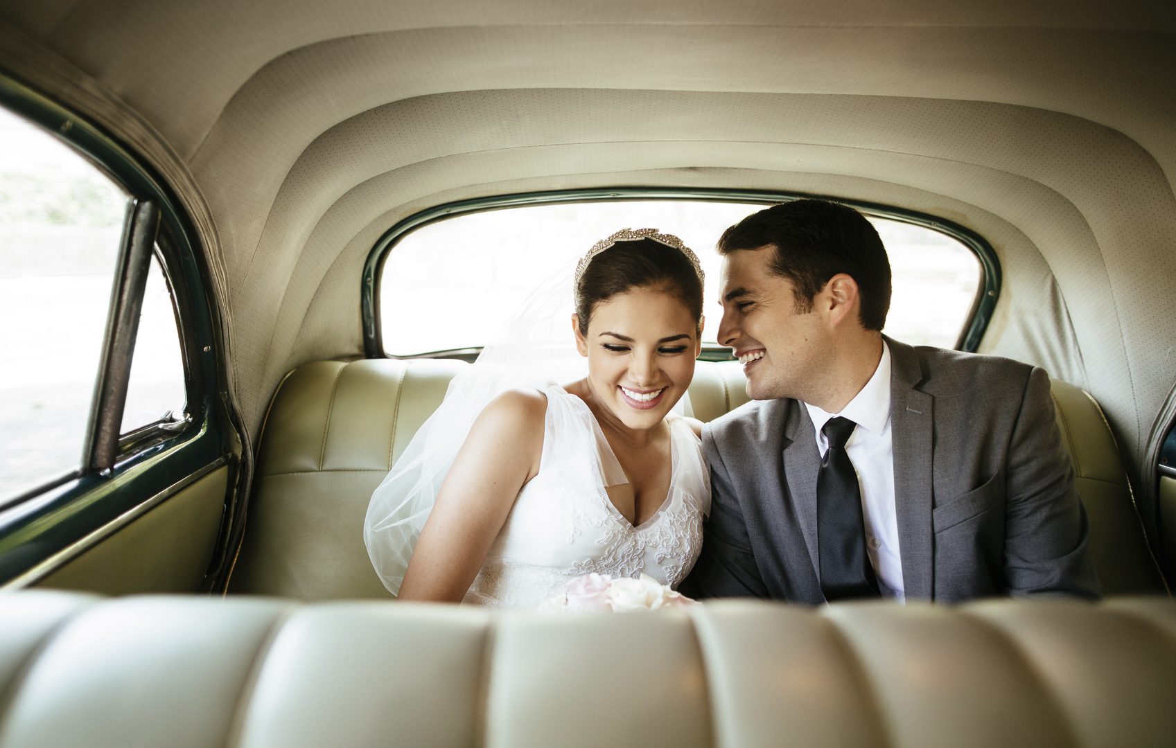 Newly married couple in their wedding clothes in the back of a car