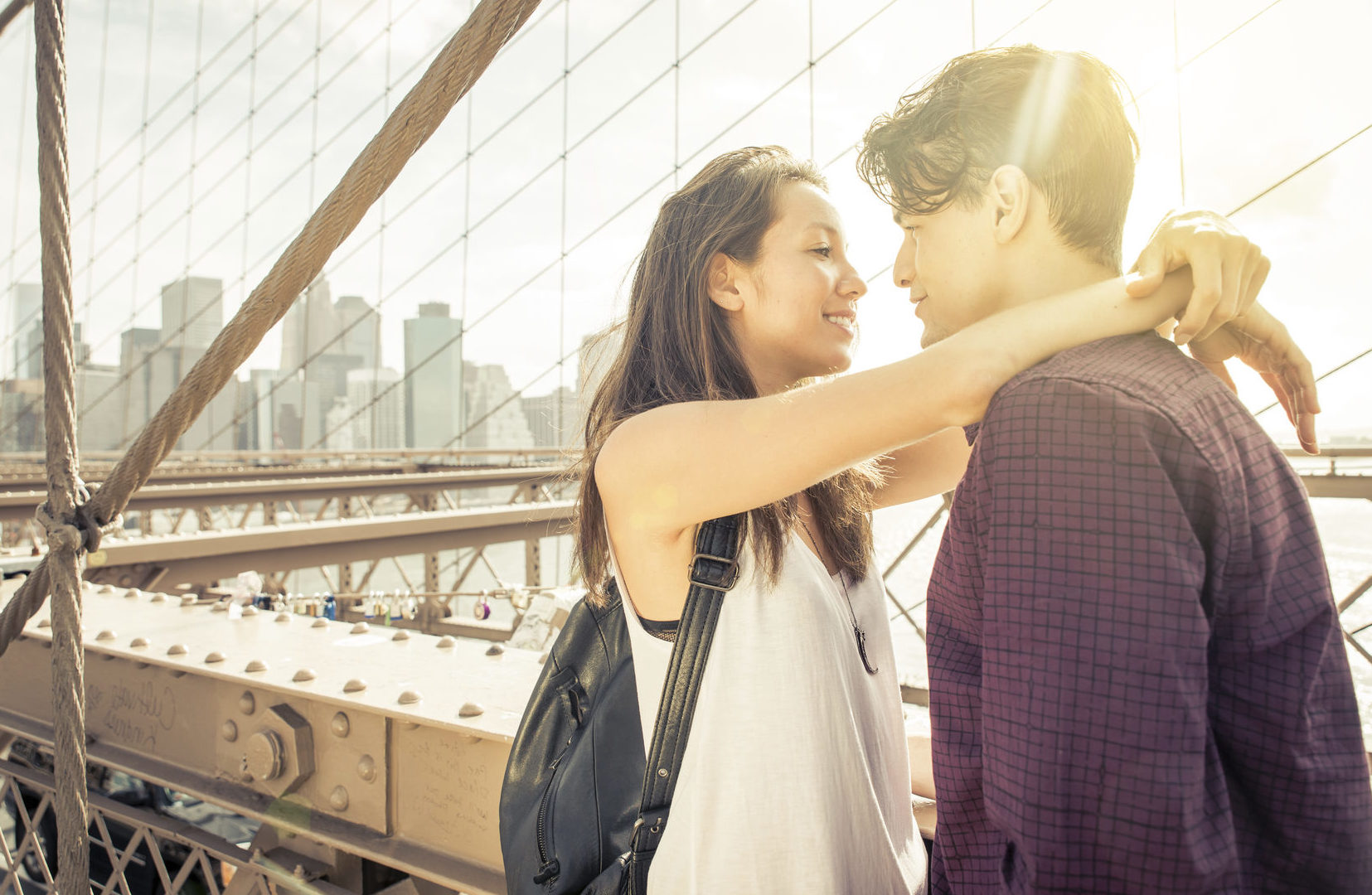 Well matched couple embracing on a bridge in the sunshine