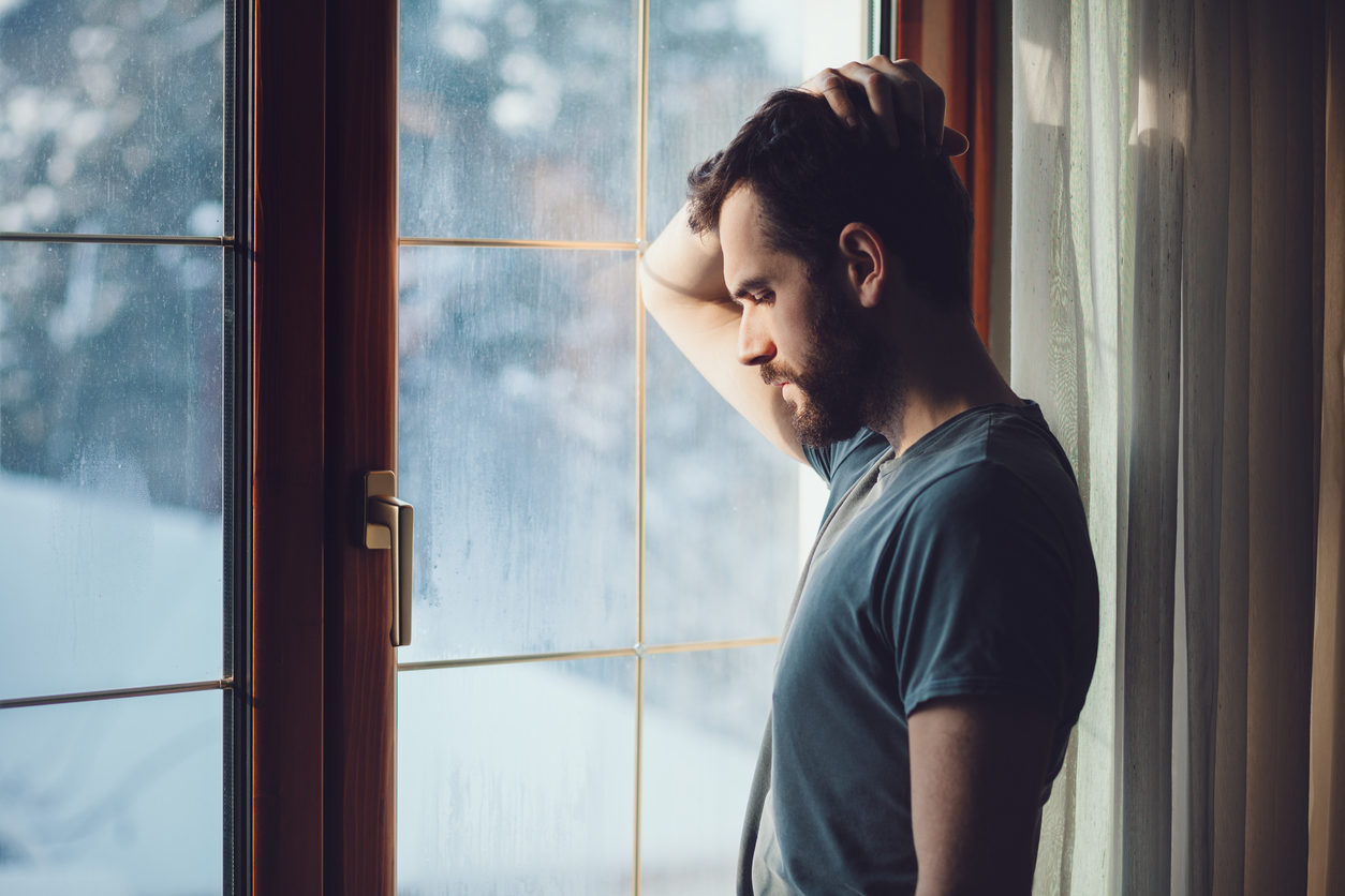 Man staring out a window processing his thoughts about faith