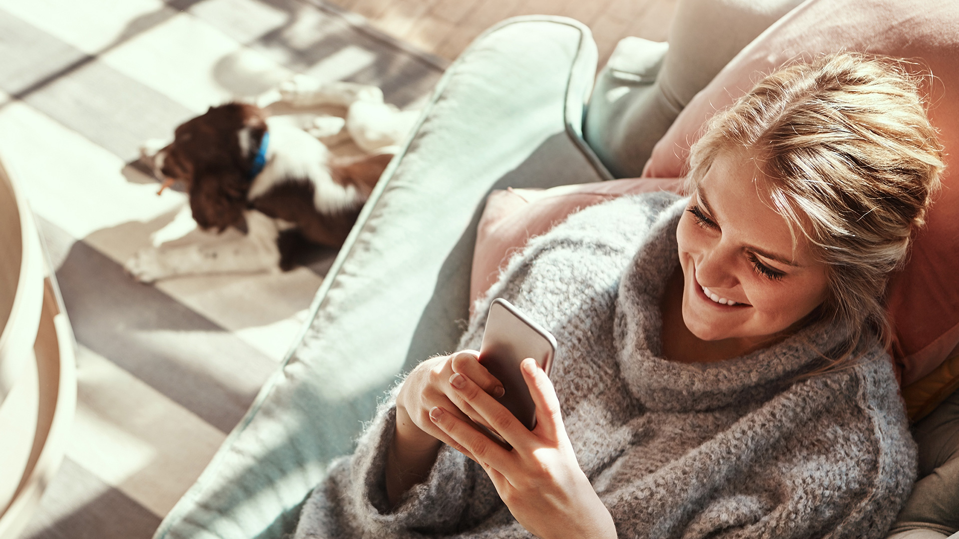 Woman lying on her sofa checking her online dating messages on her smartphone